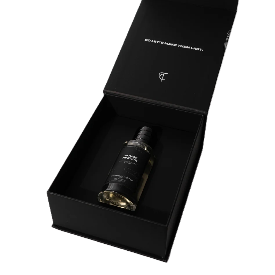 A luxury black gift box with a matching bottle of cologne inside, shown open on a white background. The box lid features white text reading 'SO LET'S MAKE THEM LAST.