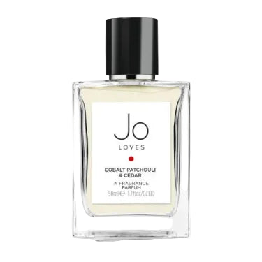 A bottle of Jo Loves Cobalt Patchouli & Cedar fragrance with a white label and a black cap.