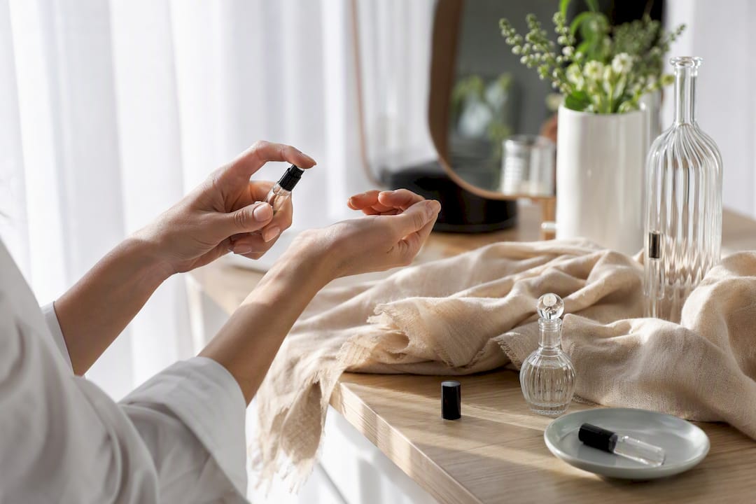 Hands testing perfume on wrist and scarf