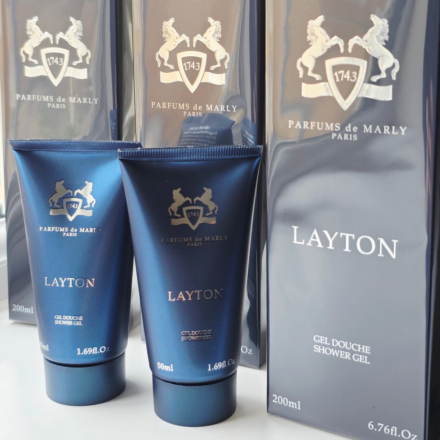 Parfums de Marly Layton shower gel packaging with blue bottles and gray box on a white background