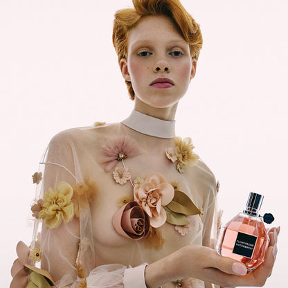 Woman holding a perfume bottle with floral dress against a white background