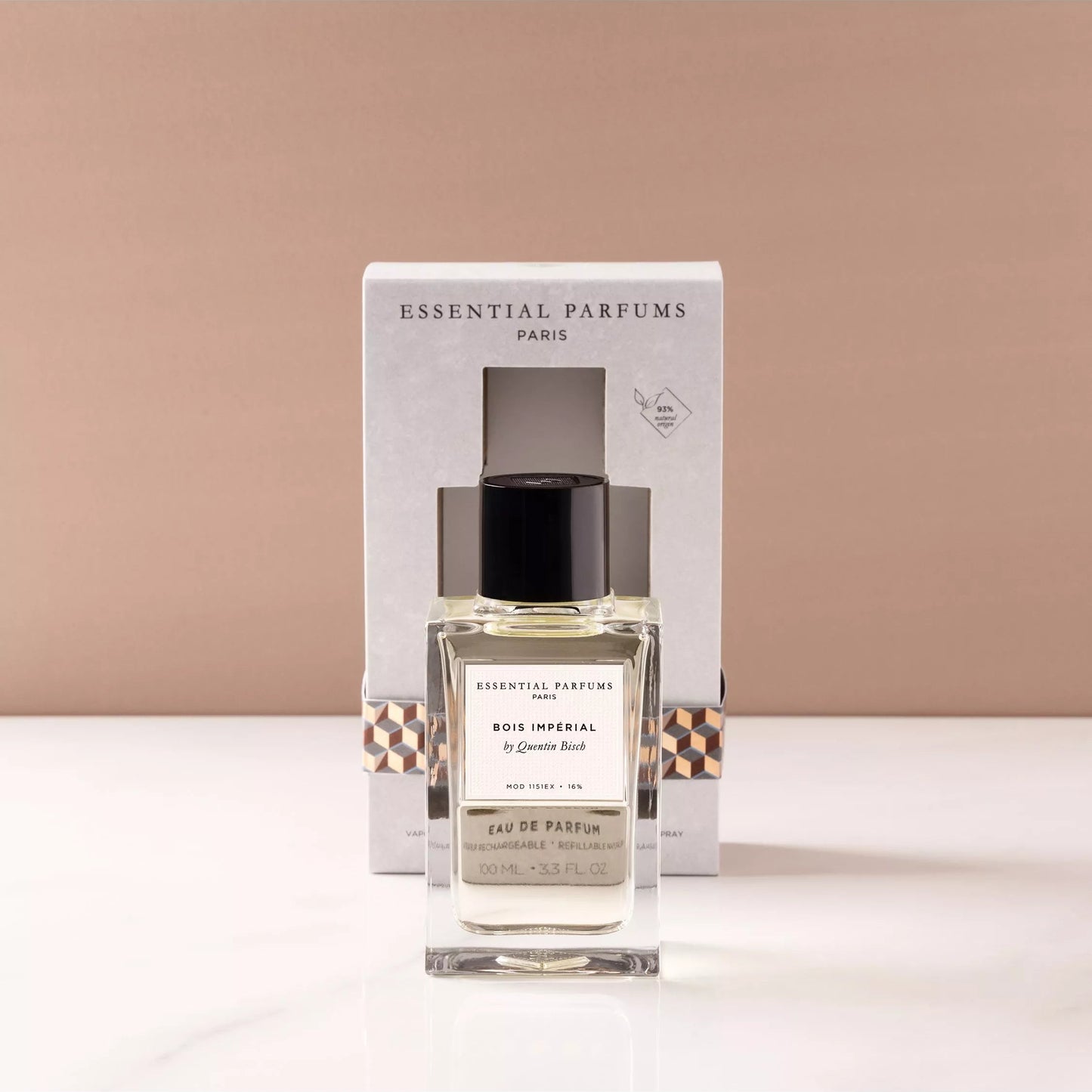A bottle of Essential Parfums Paris 'Le Bonheur' Eau de Parfum with its white packaging box, displayed on a white marble surface against a warm beige background.