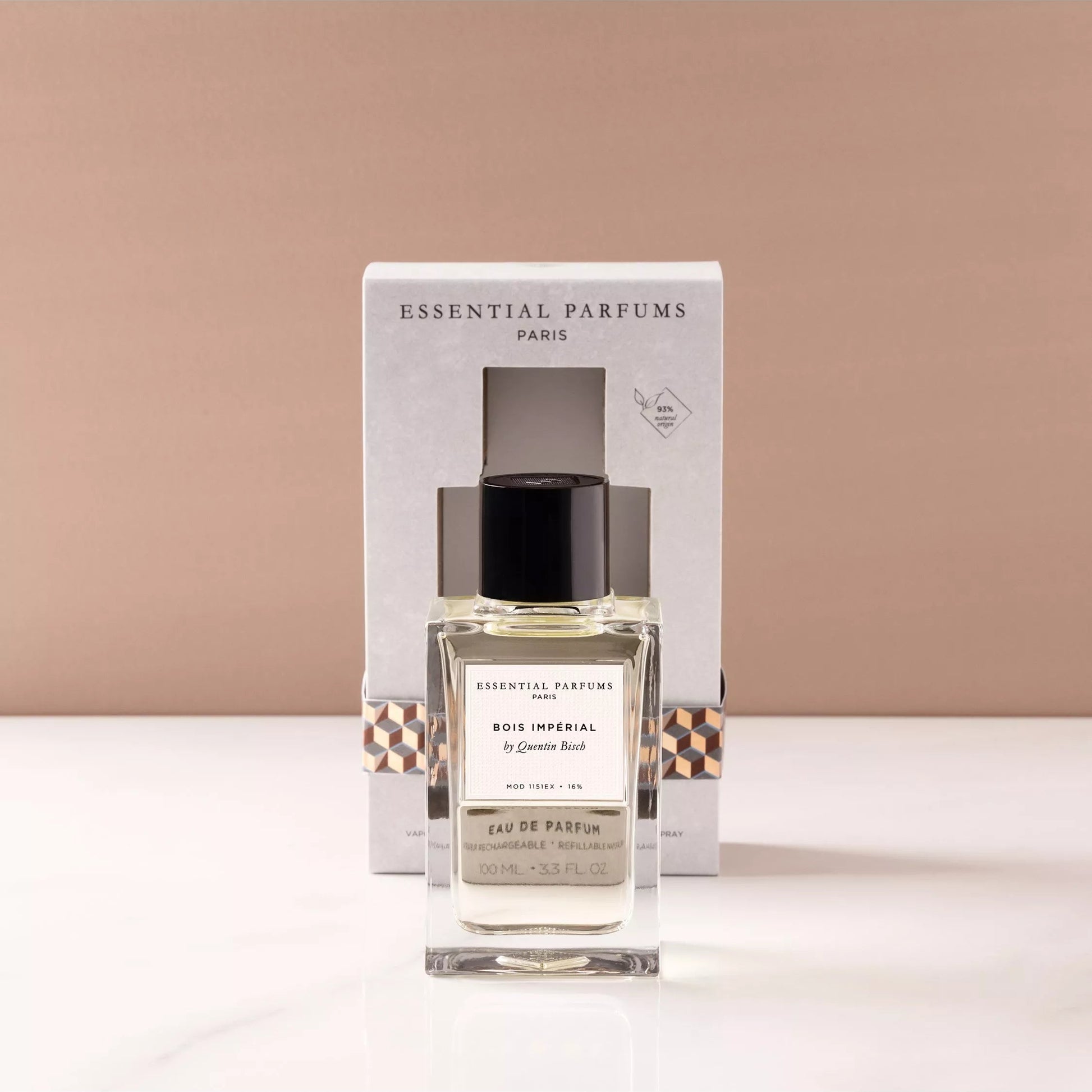 A bottle of Essential Parfums Paris 'Le Bonheur' Eau de Parfum with its white packaging box, displayed on a white marble surface against a warm beige background.