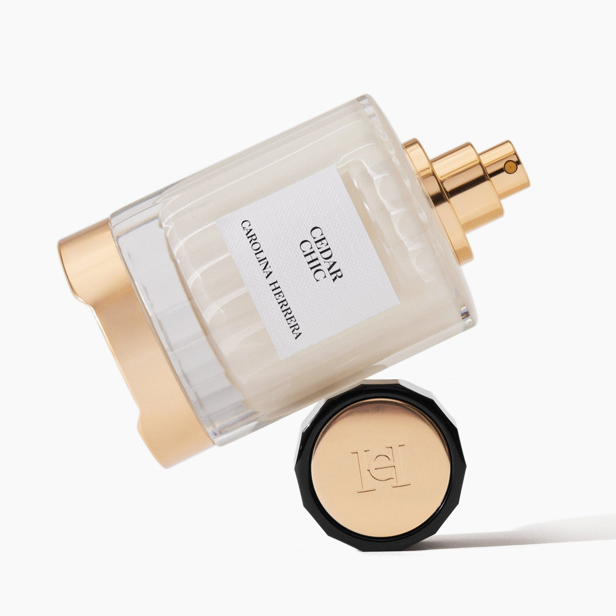 A bottle of Caron Herbertsen Cédric Côme perfume with a frosted glass body, gold spray mechanism, and a separate black cap with a gold-toned insert, set against a clean white background.