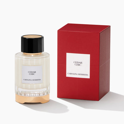 A bottle of Carolina Herrera Cedar Lake perfume next to its red packaging box, set against a clean white background.