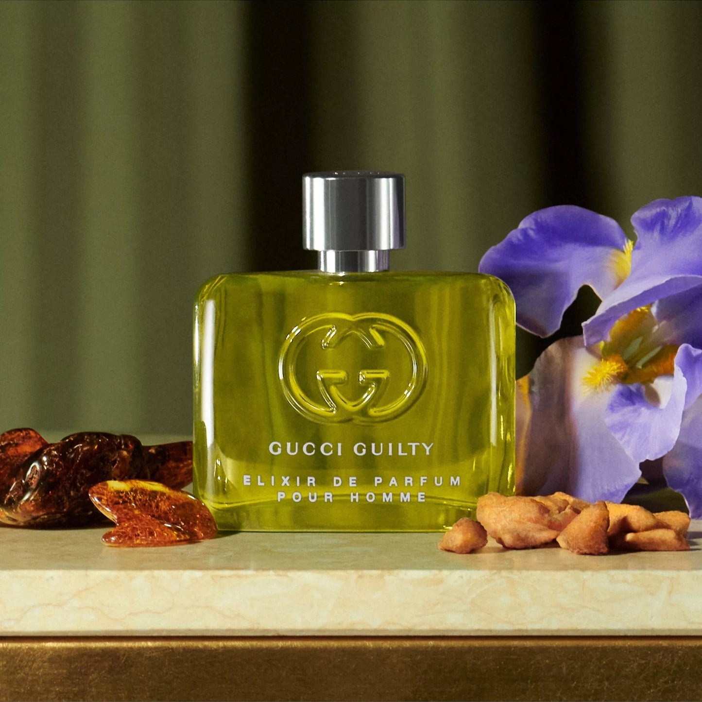 Gucci Guilty perfume bottle on a wooden surface with fruits and flowers