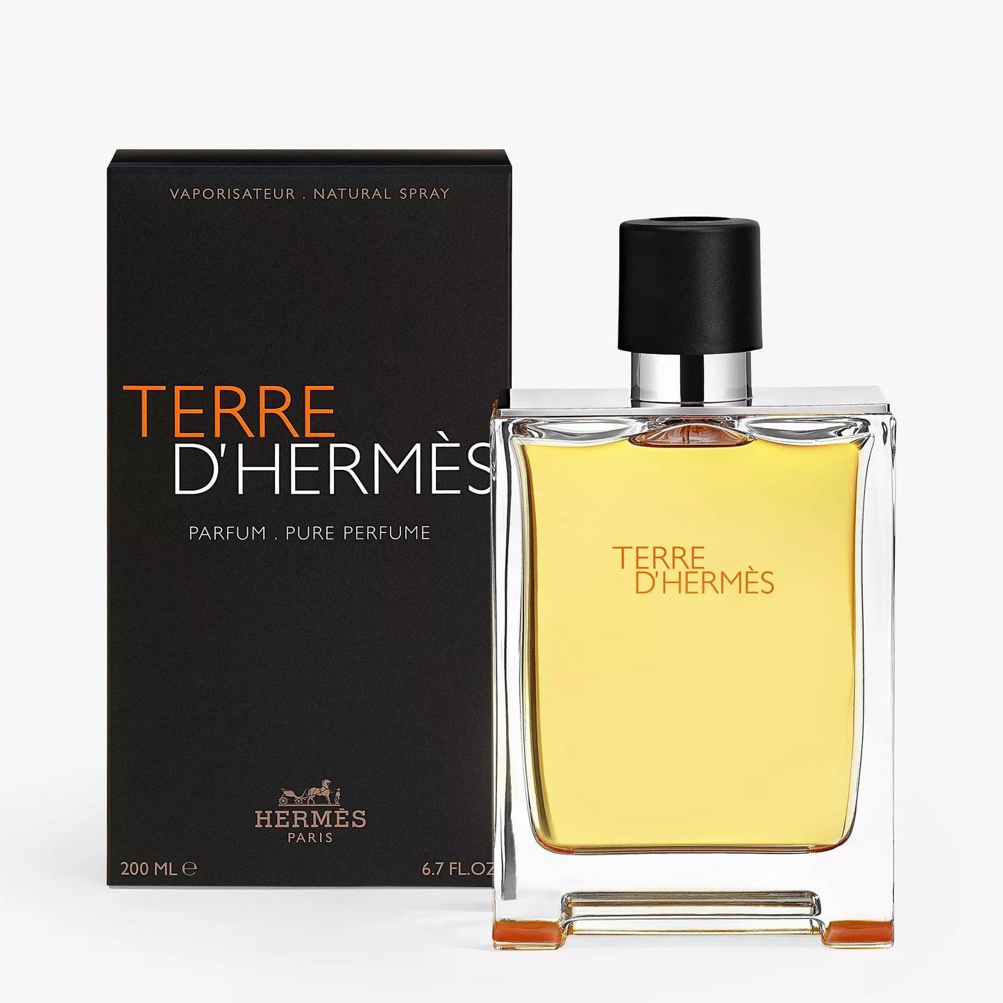 Hermes Terre D'Hermès perfume bottle with yellow liquid next to its black packaging box, on a light gray background.