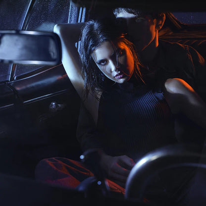 Two people sitting inside a car at night, looking at a device.