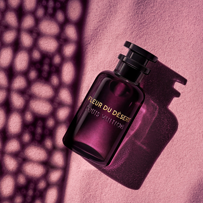 Perfume bottle labeled 'Fleur du Desert' by Louis Vuitton on a pink textured background