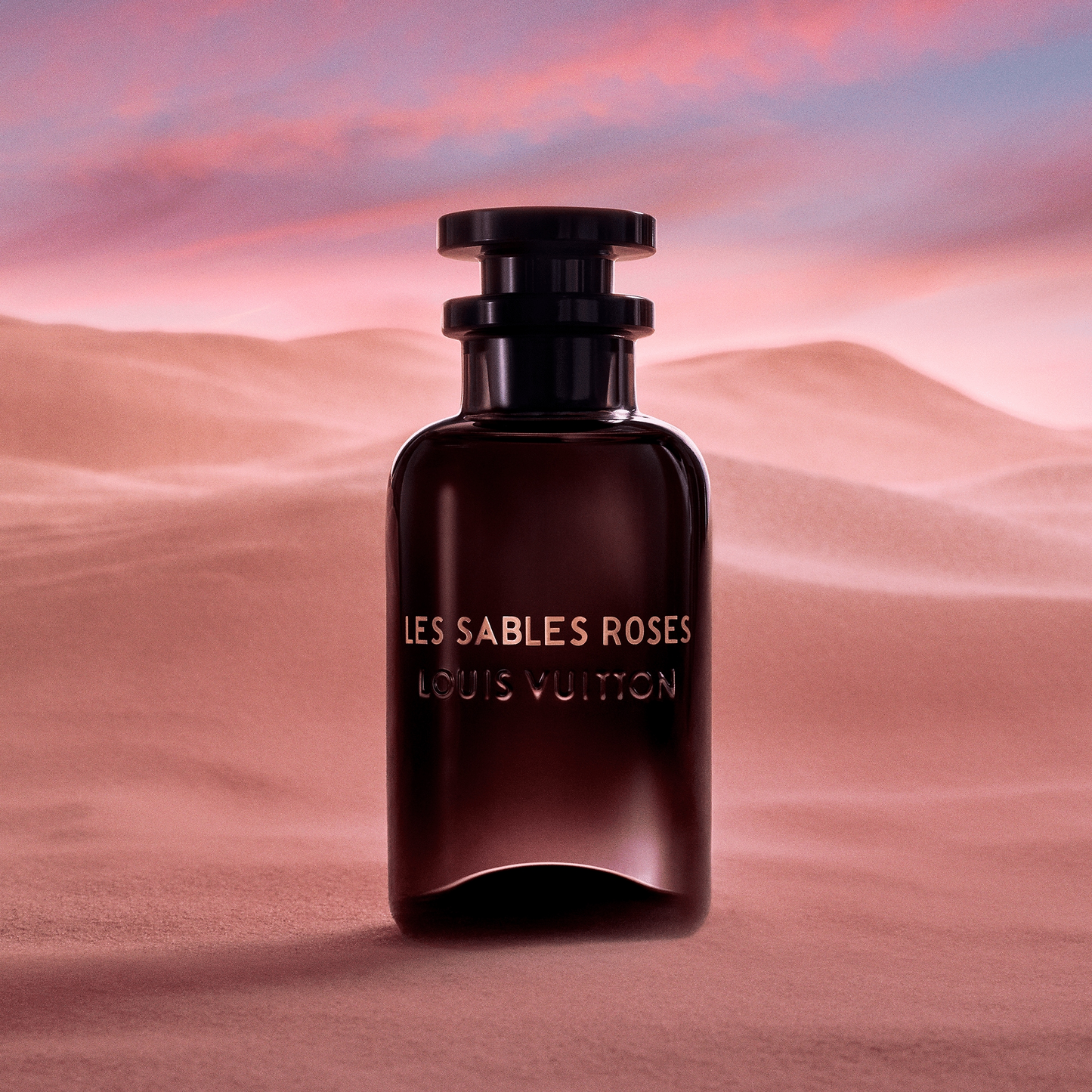 Louis Vuitton Les Sables Roses perfume bottle against a desert sunset background