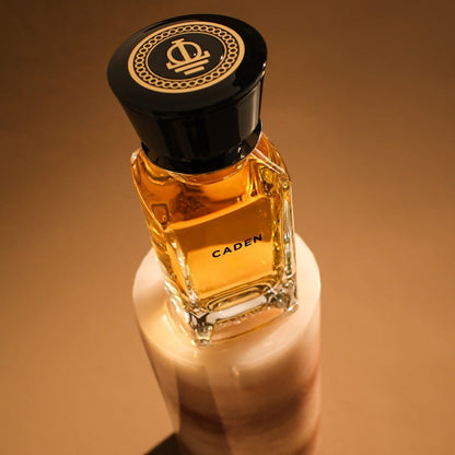 Perfume bottle labeled 'Caden' with a decorative black cap on a beige background