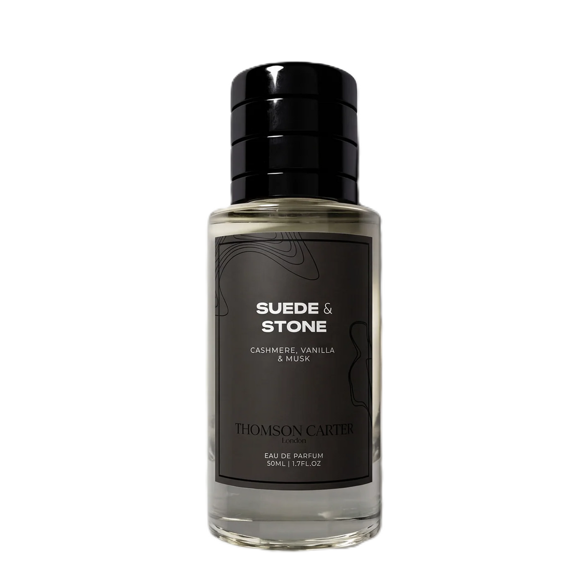 A bottle of Thomson Carter Suede & Stone Eau de Parfum, featuring a clear glass bottle with a black cap and a dark charcoal label with white text.