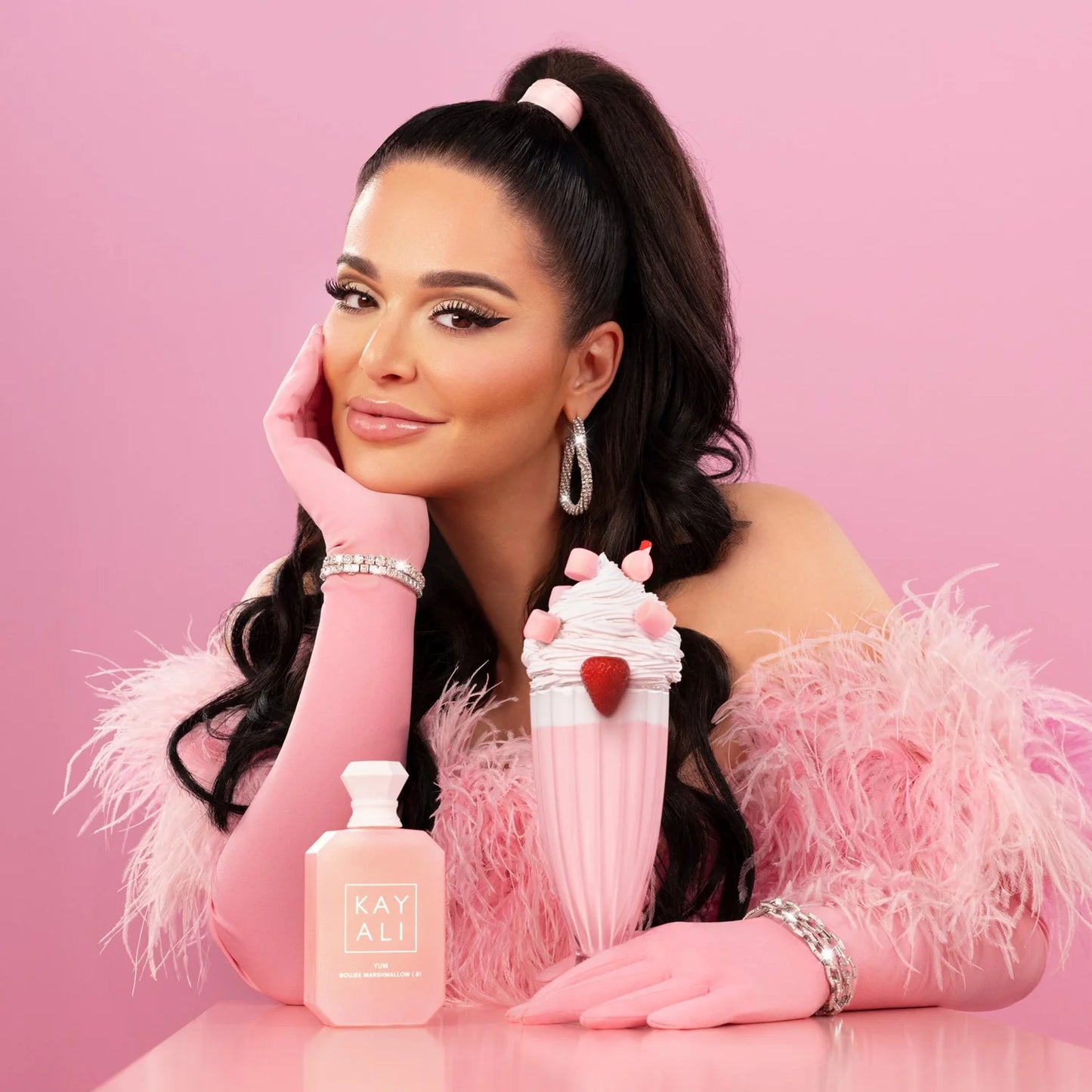 Woman holding a pink product with 'KAYALI' branding against a pink background